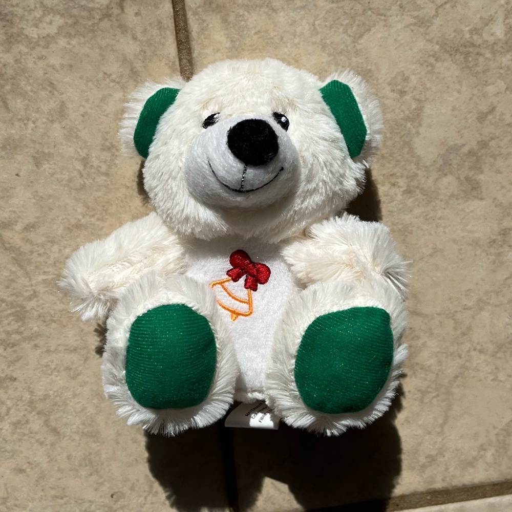 Tan teddy bear plushie with green feet and bell embroidery